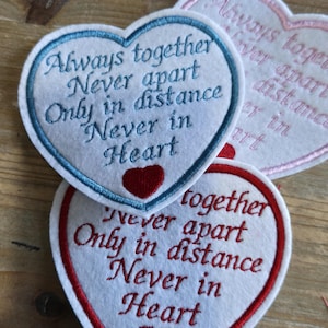 May include: Three heart-shaped patches with embroidered text. The patches are white with coloured borders and red heart accents. The text reads "Always together, Never apart, Only in distance, Never in Heart."