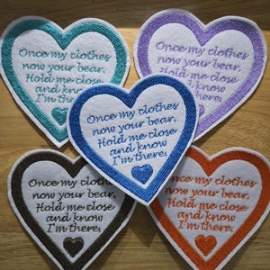 May include: Five heart-shaped patches with embroidered text: "Once my clothes now your bear, Hold me close and know I'm there." Each patch has a different colour border: teal, purple, blue, brown, and orange.