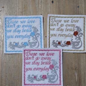 May include: Three embroidered square patches with the text "Those we love don't go away we stay beside you everyday." Each patch has a floral design and a different coloured border: blue, gold, and pink.