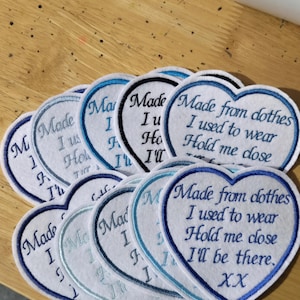 May include: Heart-shaped patches with embroidered text in shades of blue and white. The patches read "Made from clothes I used to wear Hold me close I'll be there. XX". The patches are made of a soft fabric.