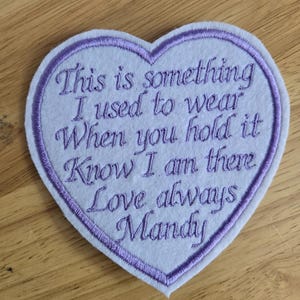 May include: A heart-shaped patch with embroidered text in purple thread on a light purple background. The text reads "This is something I used to wear When you hold it Know I am there Love always Mandy."