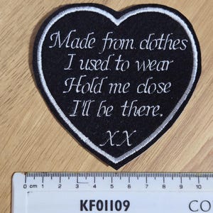 May include: Black heart-shaped patch with white embroidered text that reads "Made from clothes I used to wear Hold me close I'll be there. XX".