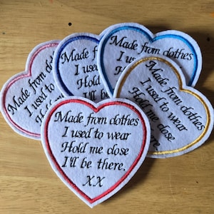 May include: A collection of heart-shaped embroidered patches. Each patch has a white center with a coloured border. The patches feature text such as "Made from clothes I used to wear." The borders are in pink, blue, red, and gold.