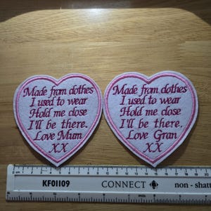 May include: Two white heart-shaped patches with pink embroidered edges. The patches have pink embroidered text that reads "Made from clothes I used to wear Hold me close I'll be there. Love Mum XX" and "Made from clothes I used to wear Hold me close I'll be there. Love Gran XX".