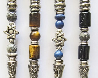 May include: Four silver-toned, hand-shaped, decorative writing implements with a star of David charm and various gemstone beads. The beads include gray, brown, blue, and black.