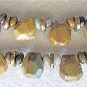 May include: A multi-strand necklace with brown, green, and gold beads. The beads are irregularly shaped and have a natural, earthy look.