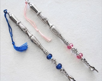 May include: Two silver-toned decorative pointers with blue and pink tassels and beads. The pointers have a star of David design on the beads.