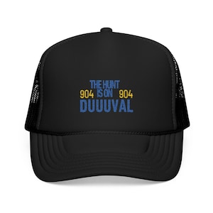 May include: Black trucker hat with a mesh back. The front of the hat has the text "THE HUNT IS ON 904 DUUUVAL" in blue and yellow embroidery.
