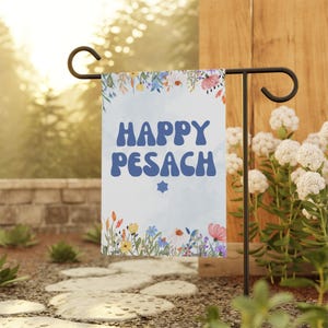 May include: A blue and white garden flag with the text "Happy Pesach" in a retro font. The flag is decorated with a floral border and a small Star of David.