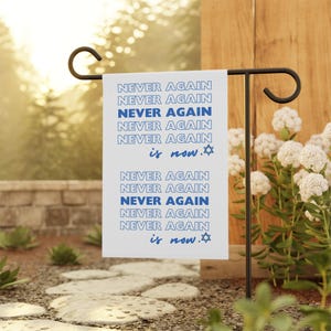 May include: A white garden flag with the text "NEVER AGAIN is now." repeated in blue lettering. A Star of David is included after the text "is now."
