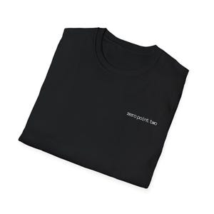 May include: Black t-shirt with the text "zero point two" in white, near the neckline. The shirt is folded and appears to be made of a soft material. The overall look is simple and minimalist.
