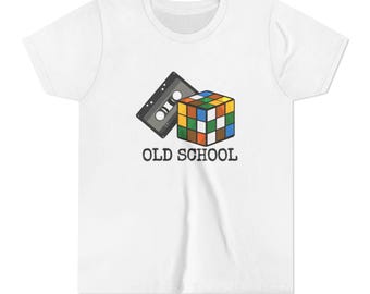 May include: White t-shirt featuring a graphic of a cassette tape and a Rubik's Cube, with the text "OLD SCHOOL" in black. The Rubik's Cube has squares of various colors. The cassette tape is gray.