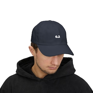 May include: Navy blue baseball cap with the number "0.2" embroidered in white on the front. The cap has a curved brim and a classic six-panel design. The hat is made of a soft, durable fabric.