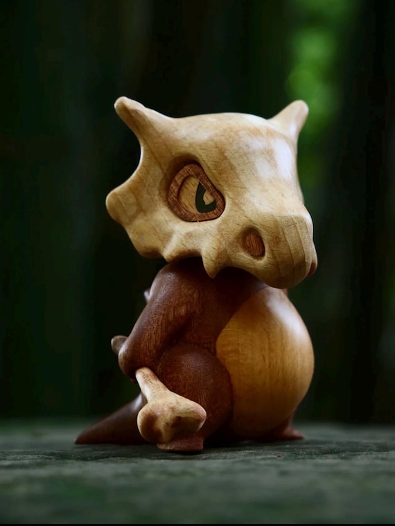 A handmade wooden Cubone figure with a magnetically detachable skull helmet — a tactile, naturalistic take on a beloved Pokémon in real carved wood.