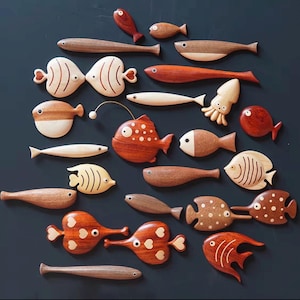 Peut inclure: Une collection de diverses créatures marines en bois, incluant des poissons, un calmar et une baudroie. Les figurines sont façonnées dans différentes teintes de bois, allant du beige clair au brun rougeâtre, avec des détails sculptés.