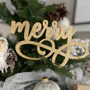 May include: Gold glitter "merry" sign hanging on a Christmas tree with white and gold ornaments.