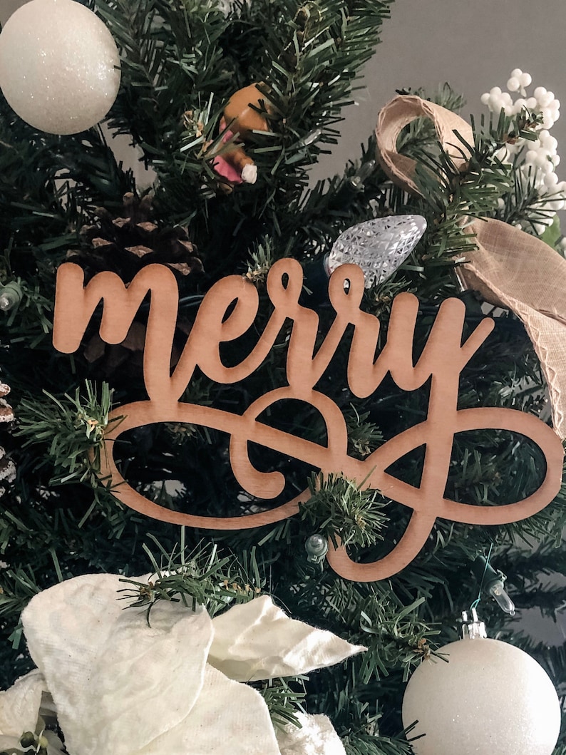 May include: A wooden Christmas tree topper with the word "merry" written in cursive.