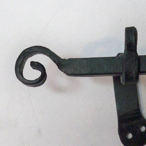 May include: Black metal curtain rod with a decorative scroll end. The rod has a bracket with two holes for mounting.