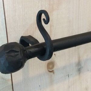 May include: Black metal curtain rod with a decorative finial and a hook on the end.