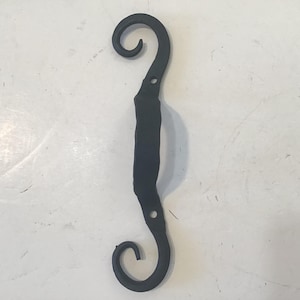 May include: Black metal door handle with a decorative scroll design. The handle is about 10 inches long.