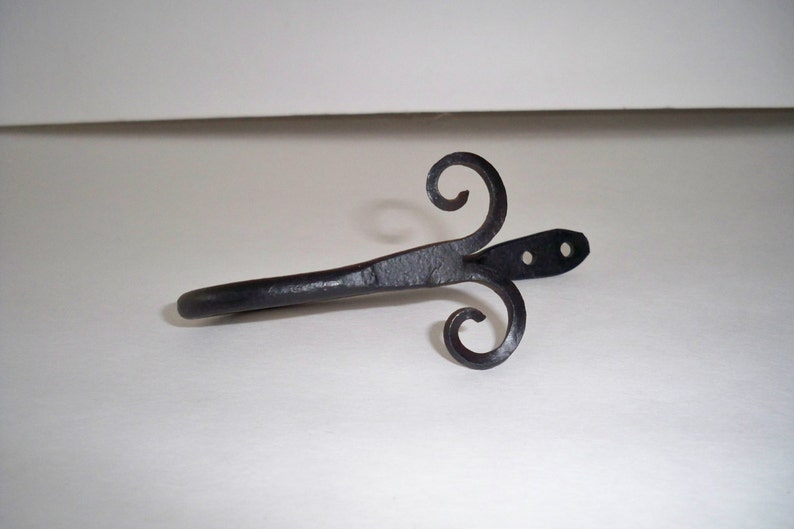 May include: Black metal curtain rod finial with a decorative scroll design. The finial has two holes for mounting.