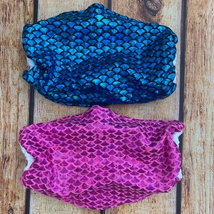 May include: Two face masks with a mermaid scale pattern. One mask is blue and the other is pink.