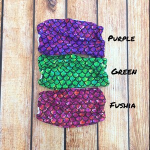 May include: Three mermaid tail fabric swatches in purple, green, and fuschia with a sparkly scale pattern. The swatches are labeled "PURPLE", "GREEN", and "FUSHIA".