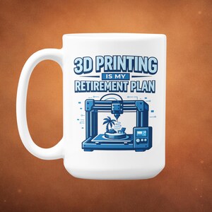 Könnte beinhalten: Weißer Keramikbecher mit großem Henkel. Der Becher zeigt den Text "3D PRINTING IS MY RETIREMENT PLAN" in Blau, zusammen mit einer blauen Grafik eines 3D-Druckers und einer tropischen Insel. Der Becher ist für Kaffee oder Tee konzipiert.