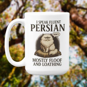 May include: White ceramic mug with a handle featuring a grumpy Persian cat illustration. The mug has the text "I SPEAK FLUENT PERSIAN" above the cat, and "MOSTLY FLOOF AND LOATHING" below. A speech bubble says "DON'T."