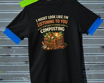 May include: Black t-shirt with the text "I MIGHT LOOK LIKE I'M LISTENING TO YOU BUT IN MY HEAD I'M THINKING ABOUT COMPOSTING." The graphic shows a wooden compost bin with vegetables, a shovel, and a worm. The sleeves have blue trim.
