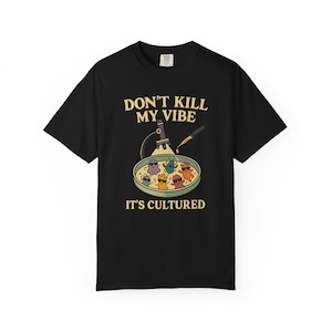 Może przedstawiać: Czarny t-shirt z napisem "DON'T KILL MY VIBE, IT'S CULTURED". Koszulka przedstawia grafikę z naczyniem Petriego z kreskówkowymi mikrobami w okularach przeciwsłonecznych pod mikroskopem.