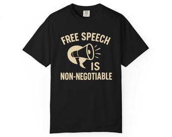 Puede incluir: Camiseta negra con el texto "FREE SPEECH IS NON-NEGOTIABLE" en color beige. El diseño incluye un megáfono. La camiseta es de cuello redondo.
