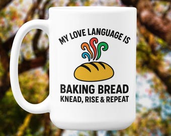Könnte beinhalten: Weiße Keramik-Tasse mit dem Text "MY LOVE LANGUAGE IS BAKING BREAD KNEAD, RISE & REPEAT". Das Design zeigt ein Brot und bunte Wirbel. Ein tolles Geschenk für Bäcker.