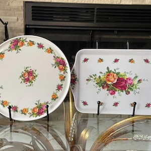 May include: A white ceramic serving plate and tray set. The plate is round, and the tray is rectangular with handles. Both feature a floral design with pink, orange, and yellow roses. The plate is 12 inches in diameter, and the tray is 14 inches long.