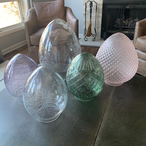 May include: Five glass lampshades in various shapes and colors. The lampshades are clear, pink, and green. They have different textures, including a diamond pattern and etched designs.