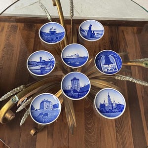 May include: A white ceramic mug with a black handle and the text "But First, Coffee" in a black, bold font. The mug is on a white surface.