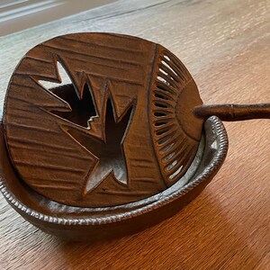 May include: A brown ceramic incense burner with a lid featuring a carved leaf design. The lid has a small handle on the side.