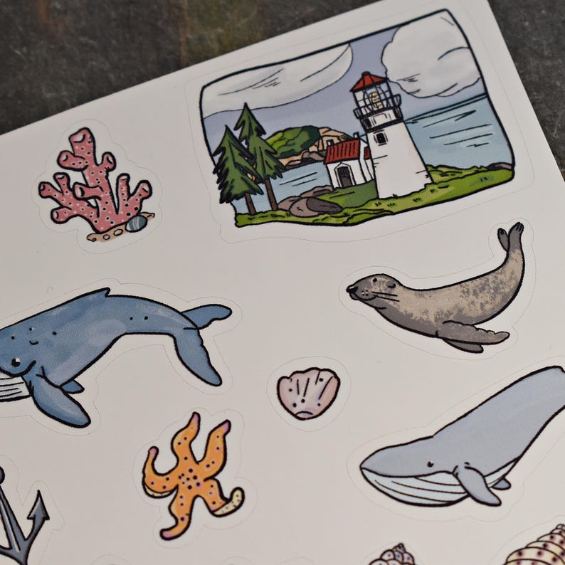 May include: A set of colourful stickers featuring ocean-themed illustrations, including a blue whale, a starfish, a coral reef, a lighthouse, a seal, and a seashell.