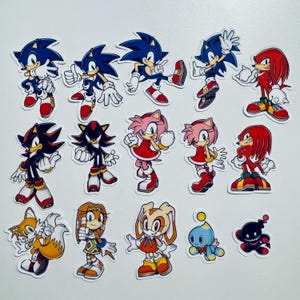 May include: A set of 14 colourful cartoon character stickers featuring Sonic the Hedgehog, Shadow the Hedgehog, Knuckles the Echidna, Amy Rose, Cream the Rabbit, Tails the Fox, and other characters from the Sonic the Hedgehog video game franchise.
