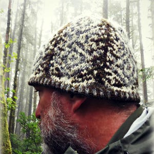 May include: A knit beanie featuring a complex, repeating geometric pattern in shades of dark brown, grey, and cream. The hat has a textured, multi-colored yarn construction with a snug fit and a visible KISDESIGNS logo in the bottom corner.