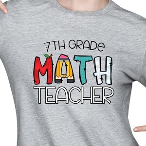 May include: A grey long-sleeved sweatshirt with the text "7th Grade Math Teacher" in colourful letters. The letters are designed to look like pencils with rubbers.