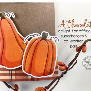May include: A card with a handwritten message that reads "A Chocolate delight for office superheroes & co-worker pals". The card features two orange pumpkins with white outlines.
