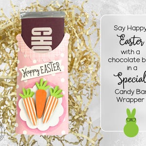 May include: Pink and white Easter-themed candy bar wrapper with a chocolate bar inside. The wrapper has a scalloped edge and a polka dot pattern. It says "Hoppy Easter" and features three cartoon carrots.
