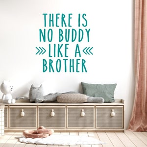 May include: Teal wall decal with the text "There is no buddy like a brother" with arrows pointing to the word "brother". The decal is on a white wall above a wooden bench with pillows and a stuffed animal.
