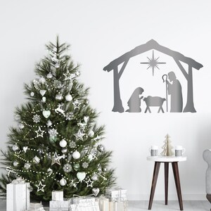 以下が含まれることがあります： オーナメントと包装されたギフトで飾られたクリスマスツリー。壁には銀色の降誕シーンのシルエットがあります。シーンには、マリア、ヨセフ、飼い葉桶の中の幼いイエス、そしてその上の星の姿が含まれています。