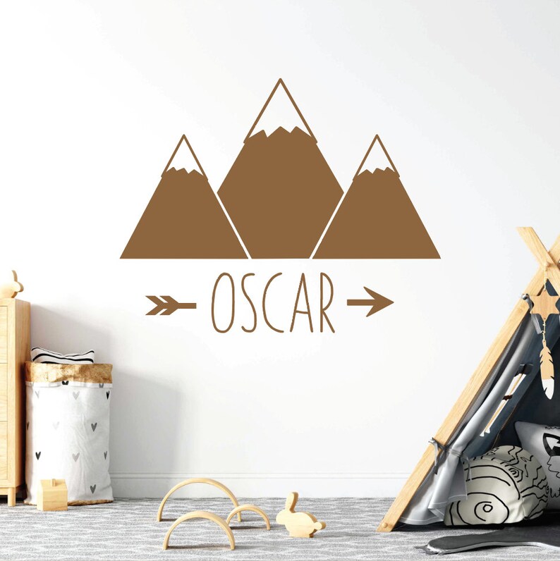 May include: Brown mountain silhouette wall decal with an arrow and the name "OSCAR" underneath.