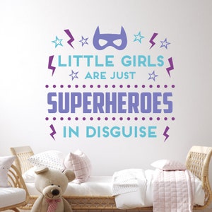 May include: Purple and blue wall decal with the text "Little girls are just superheroes in disguise". The decal features a superhero mask, stars, and lightning bolts.