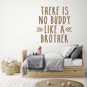 May include: A brown wall with a white quote that reads "There is no buddy like a brother" in a child's bedroom. The room has a wooden bed with a gray blanket and a stuffed fox sitting on the bed.