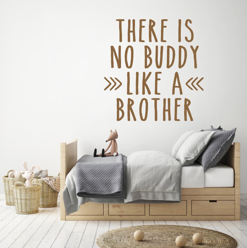 May include: A brown wall with a white quote that reads "There is no buddy like a brother" in a child's bedroom. The room has a wooden bed with a gray blanket and a stuffed fox sitting on the bed.