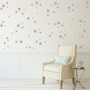 May include: A white armchair with a light blue cushion sits in front of a white wall with gray star decals.